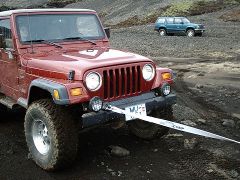 1996 Ford Bronco - A red Jeep Wrangler is in the foreground, connected to a blue SUV in the distance by a tow strap.