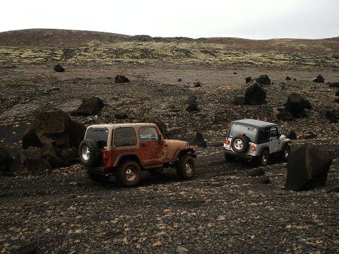 1996 Ford Bronco - Two Jeep Wranglers navigate a desolate, rocky landscape, suggesting an off-road adventure in a remote area.