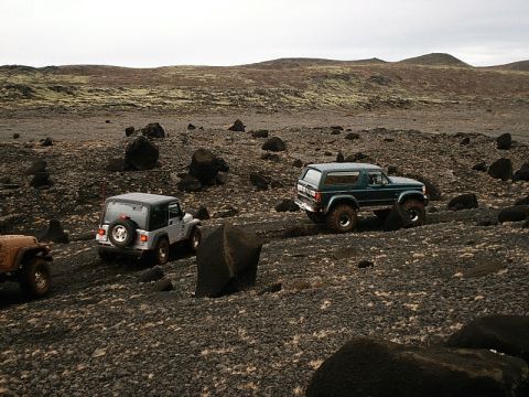 1996 Ford Bronco - Multiple off-road vehicles navigate a challenging rocky terrain under an overcast sky.