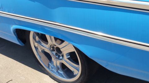 1963 Ford Galaxie - A close-up shot focuses on the rear wheel well and chrome rim of a blue vehicle.