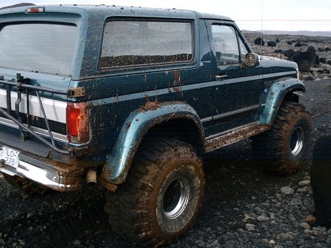 1996 Ford Bronco - This heavily modified Ford Bronco is covered in mud, suggesting recent off-road use.