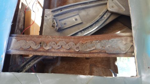 1963 Ford Galaxie - Close-up of a rusted metal channel with a decorative wavy cutout pattern, part of a window mechanism.