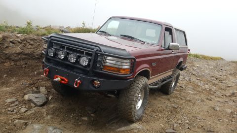 1996 Ford Bronco - A maroon Ford Bronco is parked on a dirt path with fog in the background.