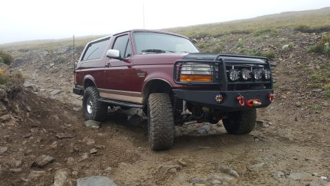 1996 Ford Bronco - This 1996 Ford Bronco is navigating a challenging off-road trail in a mountainous area.