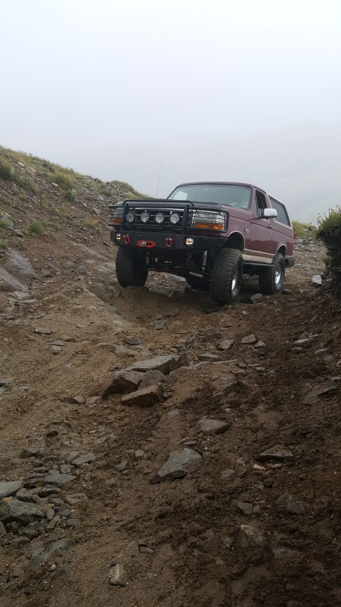 1996 Ford Bronco - A Ford Bronco navigates a challenging off-road path on a cloudy day.