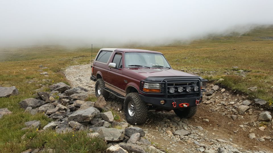 1996 Ford Bronco on a rocky mountain trail with fog in the background