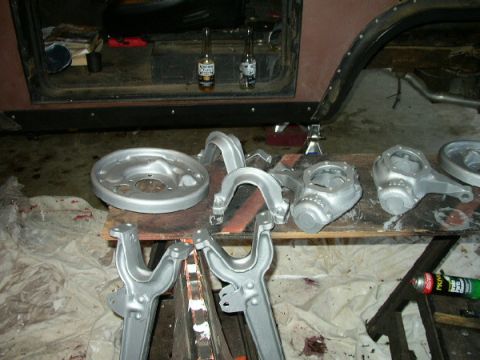 1995 Ford Bronco - Various vehicle suspension components and a brake drum are laid out on a workbench for repair or restoration.