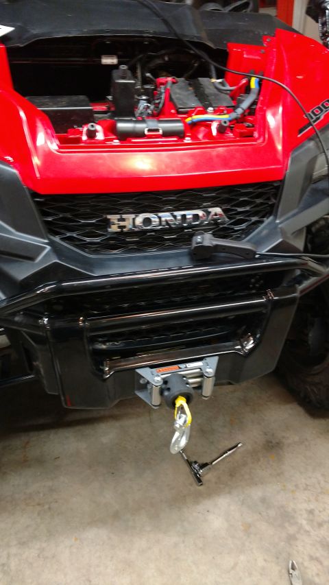 2016 Honda TRX 90 - A Honda ATV is shown from the front, a winch mounted below the grille and an open hood revealing its engine bay.