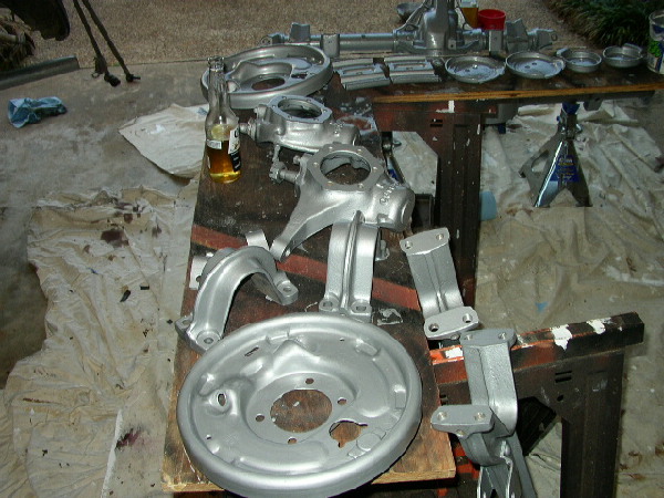 Silver painted suspension parts and brake drum on a workbench