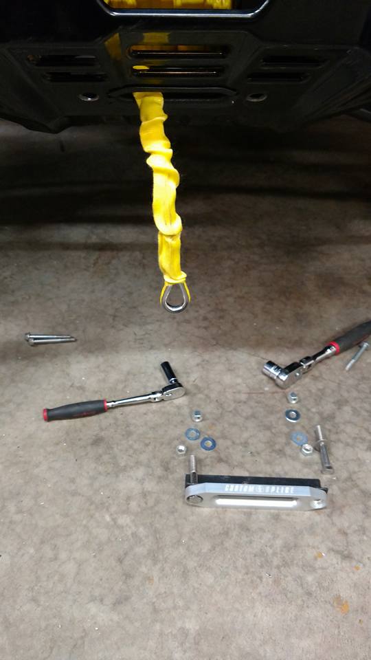 Silver winch part with yellow rope and tools on concrete floor