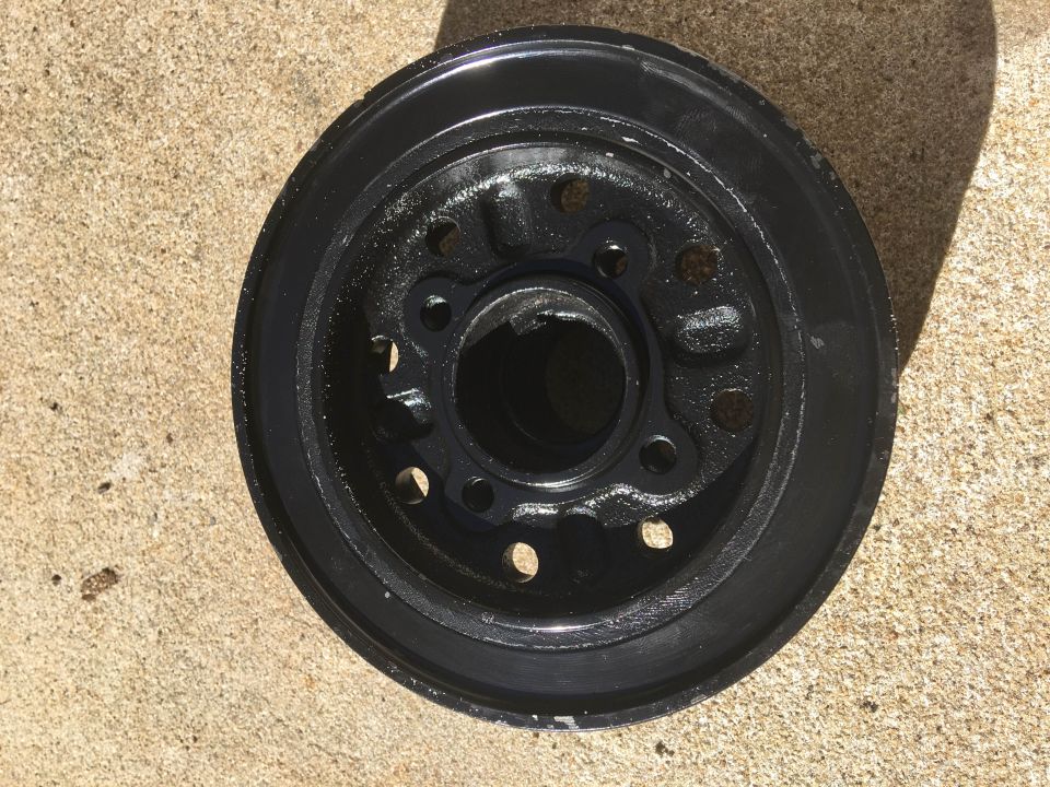 Black pulley with multiple bolt holes and a central opening