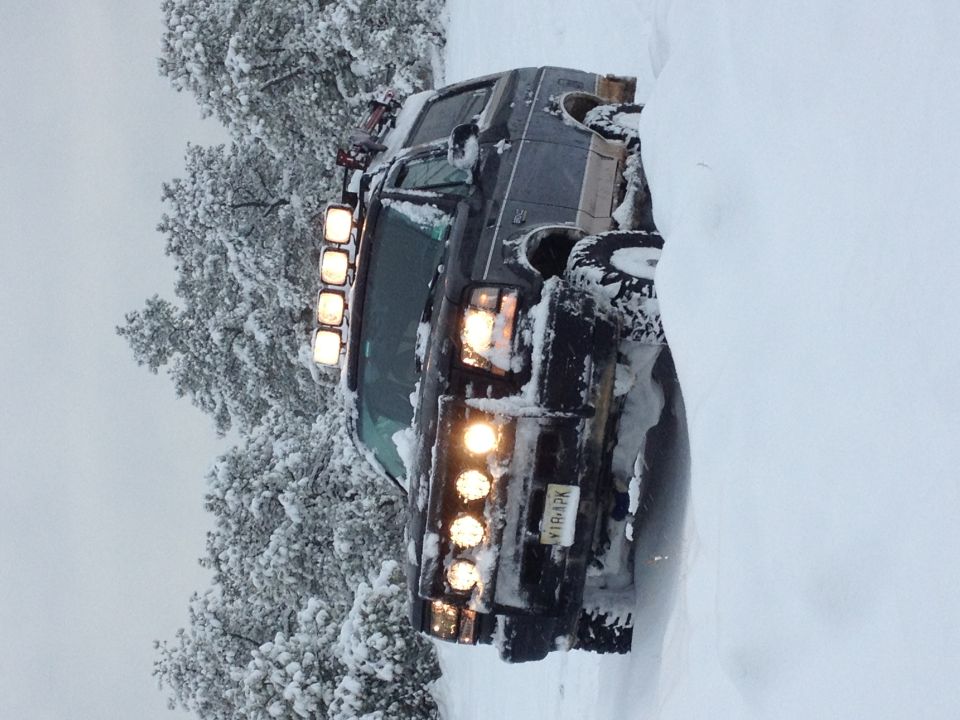 1996 Ford Bronco stuck in deep snow, with extra lights on the roof rack