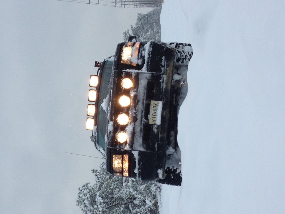Black SUV with roof lights stuck in snow, rear view
