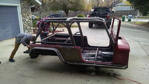1985 Jeep CJ7 - A Jeep CJ body is being worked on in a driveway, with a roll cage and custom frame modifications visible.