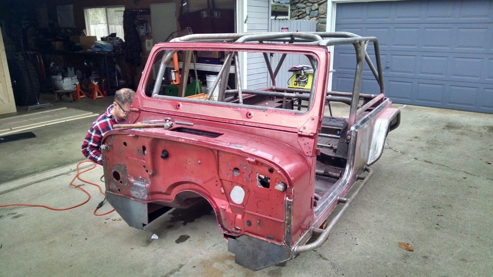 Red Jeep CJ body with roll cage, undergoing restoration