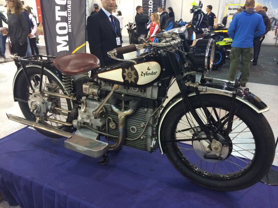 Black motorcycle with a brown seat and "4 Zylinder" text on the side