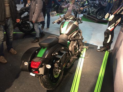 1987 Ford Bronco - A black and green motorcycle is displayed indoors with other vehicles and people around.