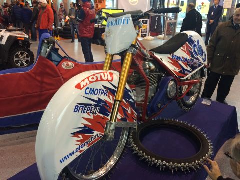 1987 Ford Bronco - A speedway motorcycle is displayed with a studded tire, Russian text and a website address.