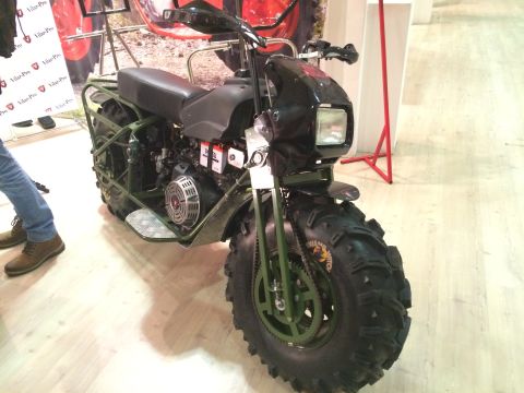 1987 Ford Bronco - This all-terrain motorcycle features oversized tires and a visible engine, presented indoors.