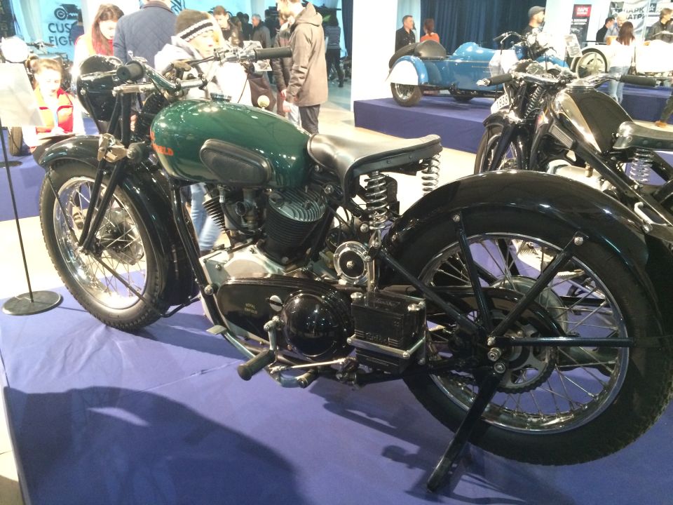 Green motorcycle side view with black fenders and spoked rear wheel