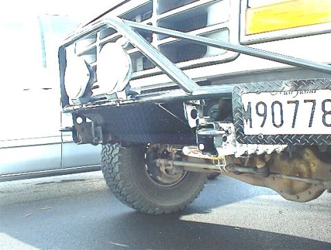 1995 Ford Bronco - A white Ford Bronco's rear bumper and tire are visible, with a custom brush guard and auxiliary lights attached.