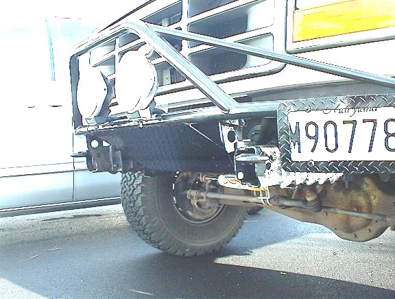 Rear bumper and tire of a white Ford Bronco with a custom brush guard and auxiliary lights
