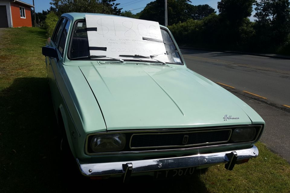 Light green sedan with a sign on the windshield saying $1800 and a phone number
