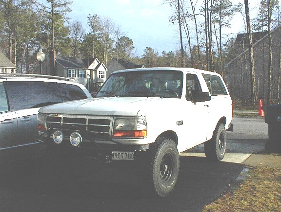 White 1995 Ford Bronco with aftermarket lights and a license plate reading 1907780