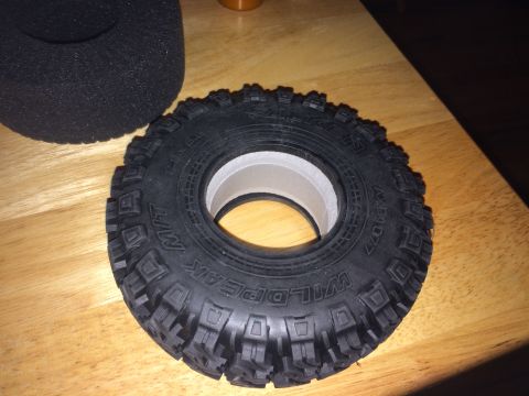 1989 Ford Bronco - A close-up view of a single off-road tire and its foam insert, resting on a wooden surface.