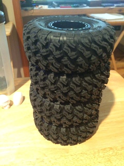 1989 Ford Bronco - Four RC car tires are stacked on a wooden surface.