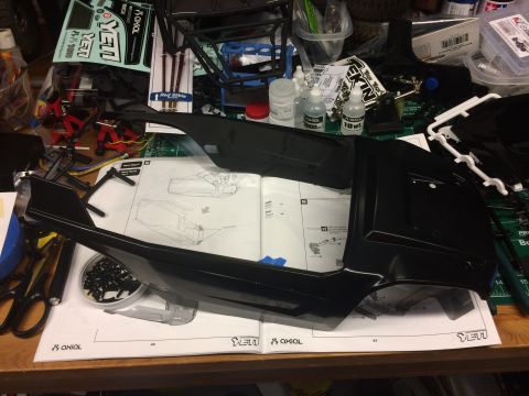 1989 Ford Bronco - A partially assembled remote control car body sits on top of its instruction manual, surrounded by hobby supplies.
