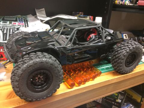 1989 Ford Bronco - RC rock crawler with roll cage and off-road tires is displayed on a wooden surface.