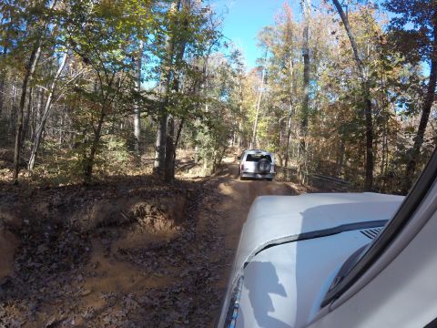 1979 Ford Bronco - Two SUVs navigate a wooded trail during autumn, with a watermark visible.