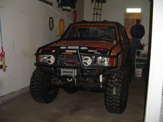 Orange off-road SUV with large tires and a winch, parked in a garage