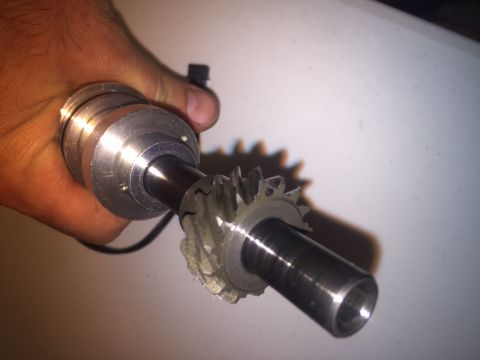 1982 Ford Bronco - A hand holds a metal shaft with a gear attached. The gear appears to be damaged with several teeth broken off.