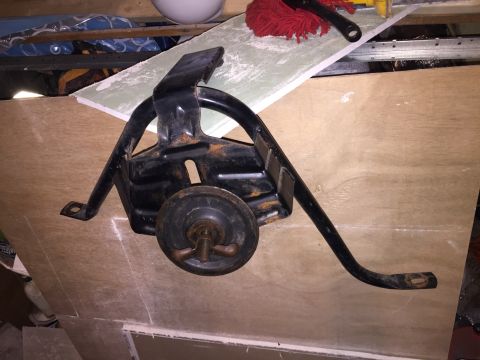 1967 Ford Custom Wagon - A black metal spare tire mount with a wingnut and wheel is shown resting on a piece of plywood. The mount appears to be rusted in several p…