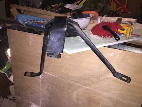 1967 Ford Custom Wagon - A black metal automotive part, possibly a suspension component, is laid out on a surface of plywood and other construction materials. The p…