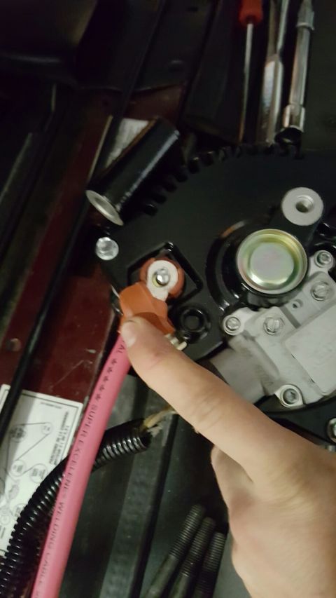 1996 Ford Bronco - A person's hand is shown connecting a thick red wire with an orange connector to a black automotive component, likely an alternator. The co…