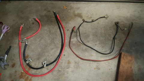 1996 Ford Bronco - Two sets of battery cables are laid out on a concrete floor. One set is red and black, and the other is black and red. Tools and scissors a…