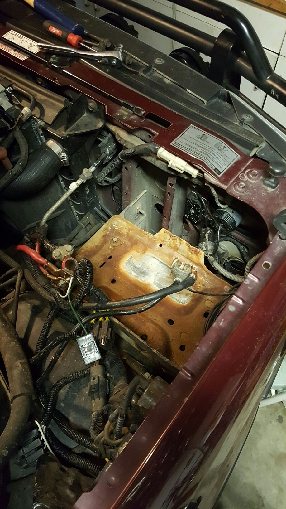 1996 Ford Bronco engine bay with rusted battery tray and wiring.