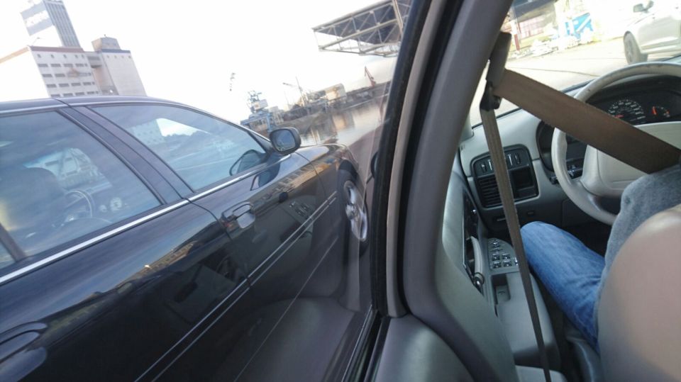 View from inside a car looking out the passenger side window at a black sedan.