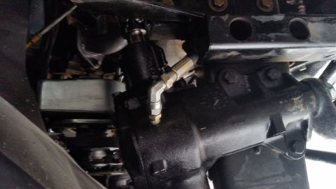 1979 Ford Bronco - This image shows a close-up view of a vehicle's steering mechanism, specifically the power steering gearbox and its associated hydraulic li…