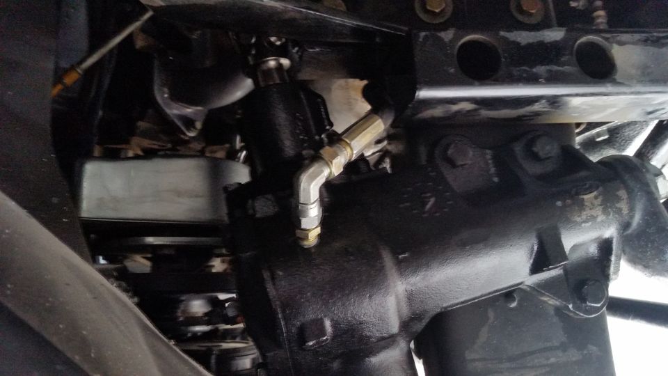 Close-up of a vehicle's power steering gearbox with hydraulic lines attached
