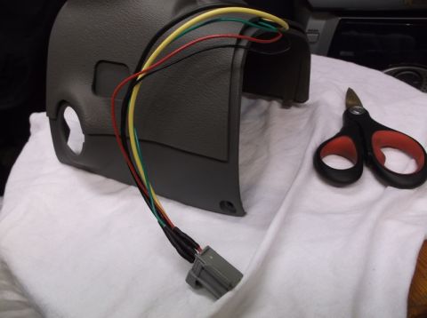 1999 Mercury Grand Marquis - A gray plastic steering column cover with multiple wires leading to a gray connector is shown on a white cloth. A pair of black and red han…