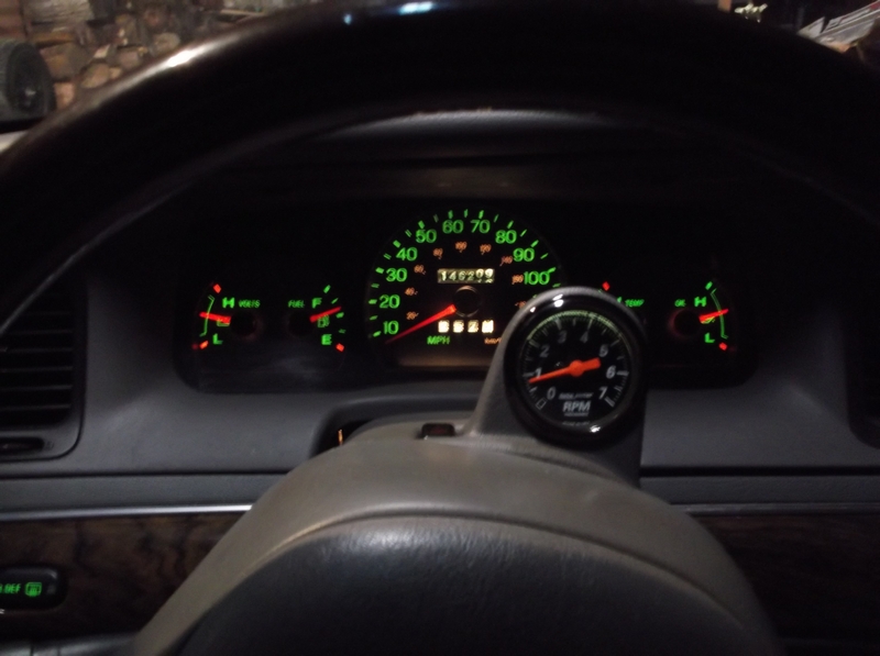Vehicle dashboard with illuminated gauges including speedometer, tachometer, fuel, and voltmeter.