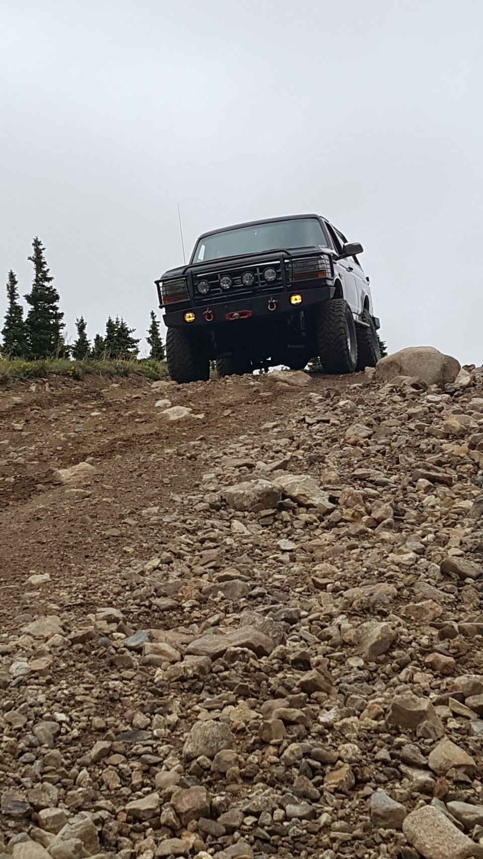 Dark Ford Bronco on rocky trail, front view.