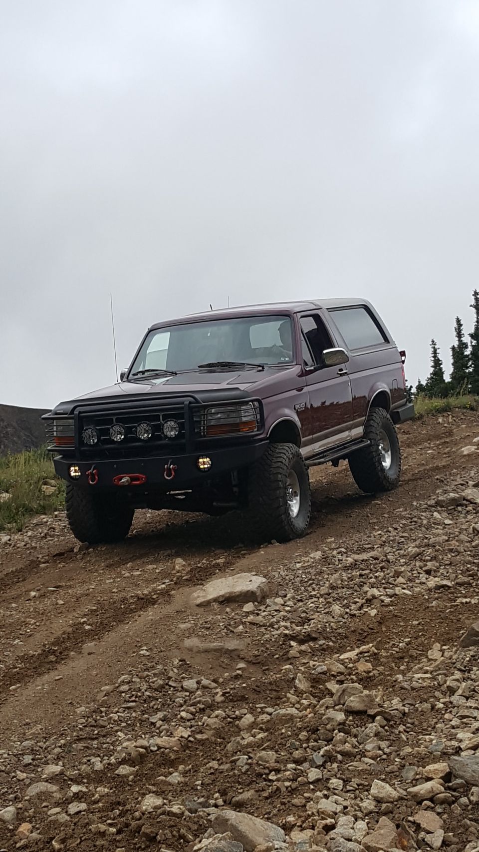 Maroon 1996 Ford Bronco on a rocky off-road trail.