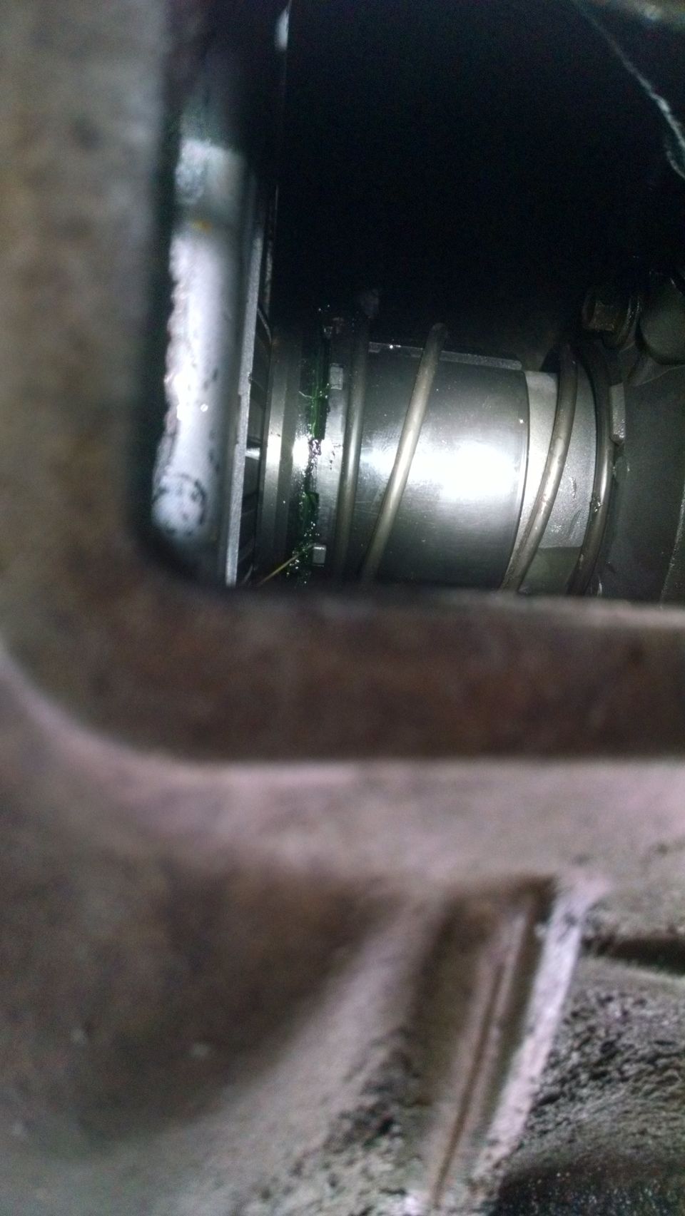 Close-up of a metal component with green grease, likely part of a vehicle's drivetrain or suspension.