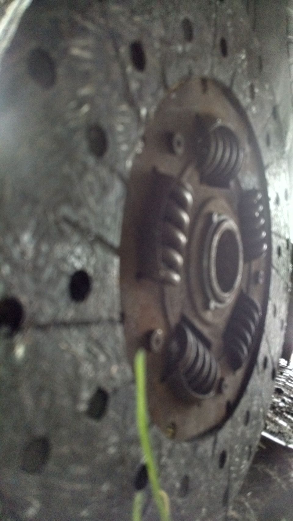 Close-up of a vehicle clutch disc with springs and holes.