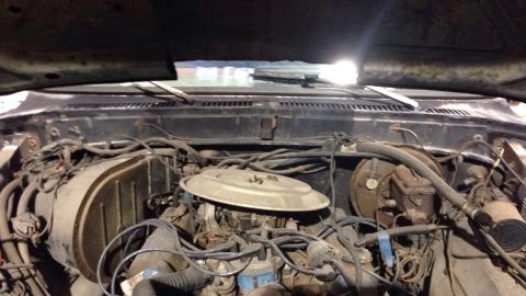 1979 Ford Bronco - The engine bay of a vintage Ford Bronco is shown, with the hood open. The view looks down into the engine compartment, revealing the engine…